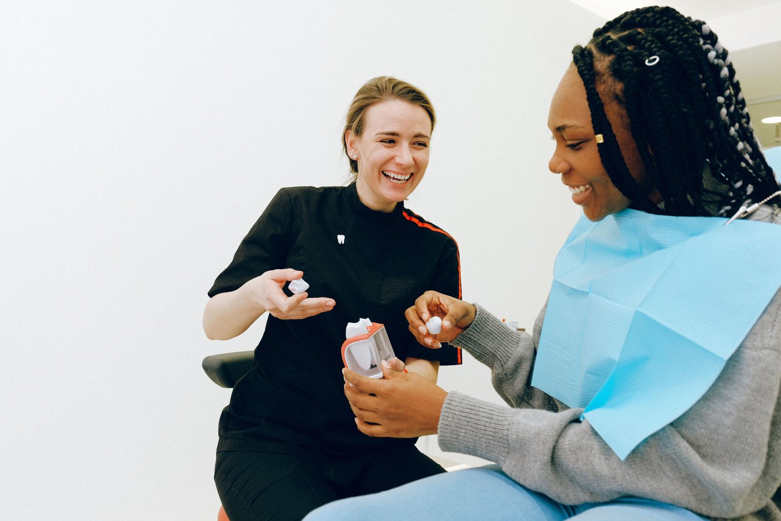 A dentist showing a dental model to a smiling patient during a consultation