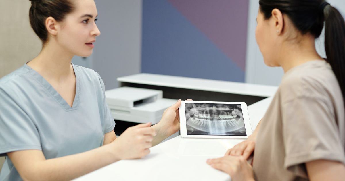 Dentist reviewing a dental X-ray on a tablet with a patient during a digital treatment-planning consultation.