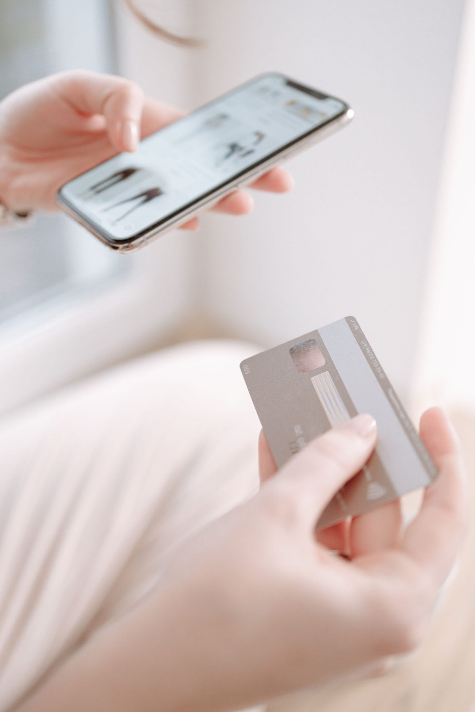 Hands holding a smartphone and credit card together, depicting online shopping and digital payment methods