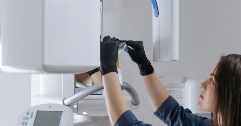 Dental technician positioning a cone-beam style imaging unit before a scan.