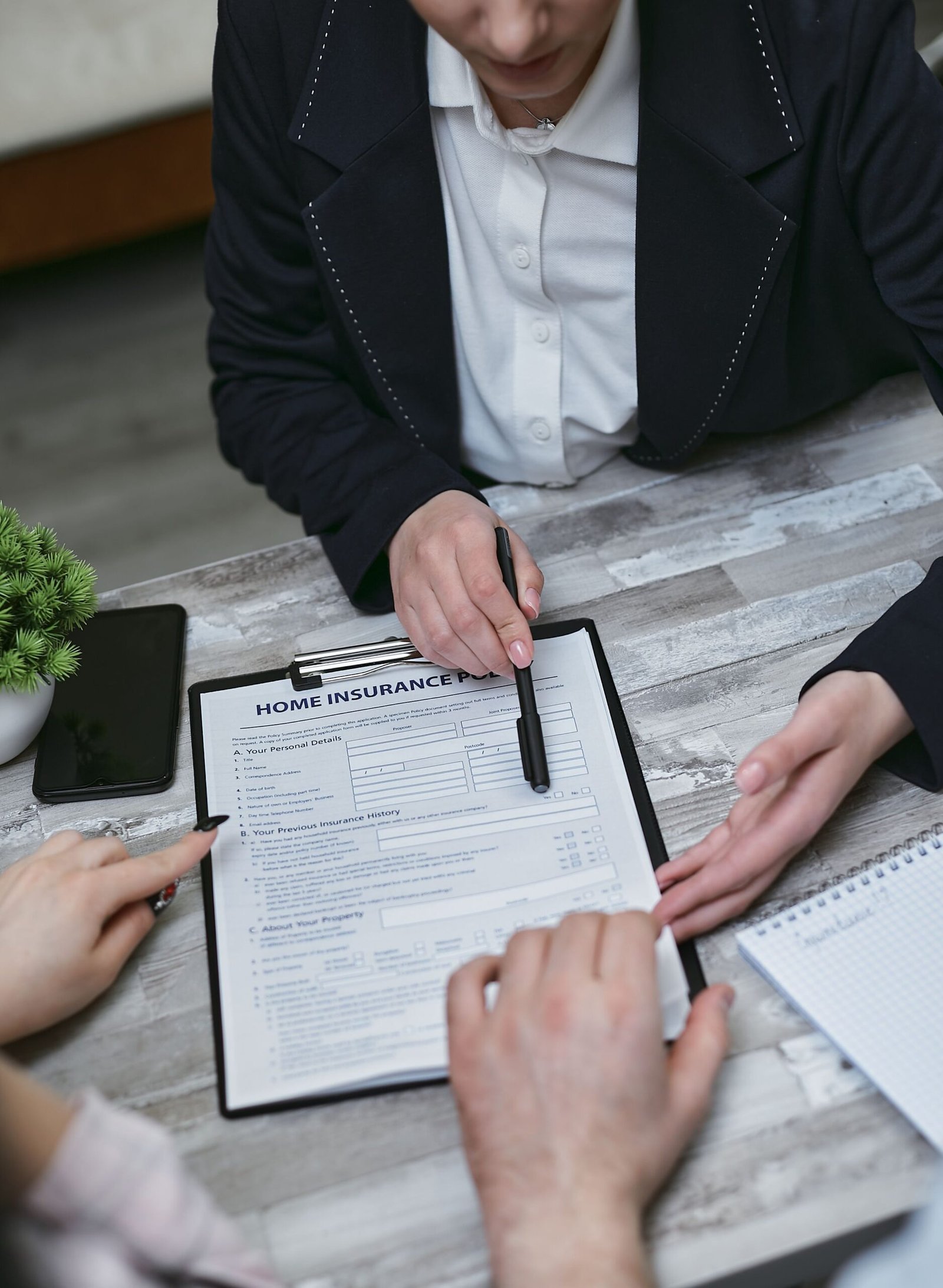 An insurance agent presents and discusses home insurance paperwork with clients seated at a meeting table during a consultation