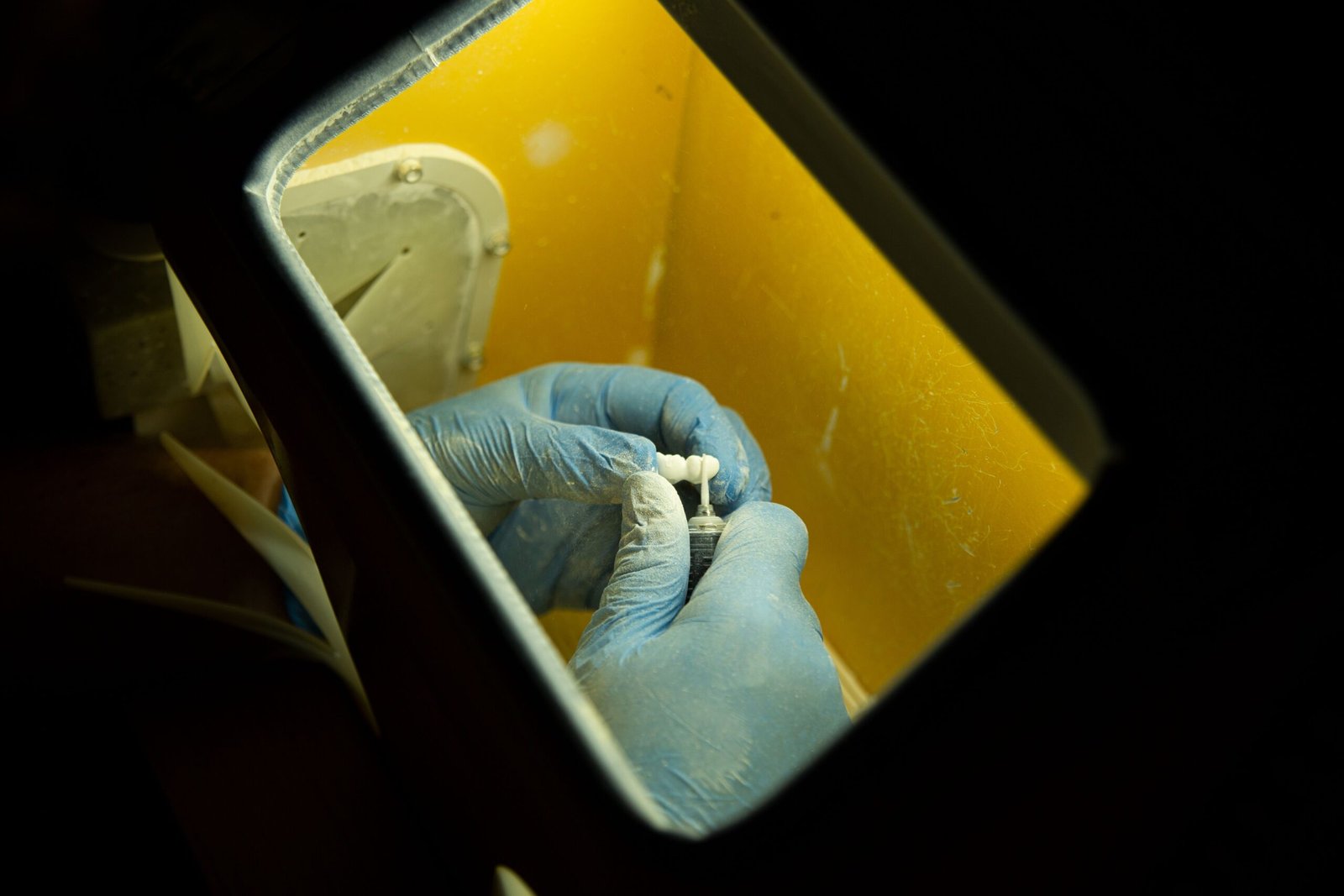 Close-up overhead view of a dental professional wearing latex gloves working on a dental implant using precision instruments in a laboratory setting