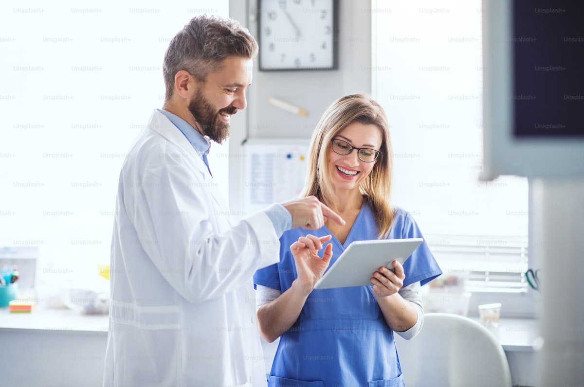 Dentist and assistant reviewing a digital implant treatment plan on a tablet in a modern dental clinic.