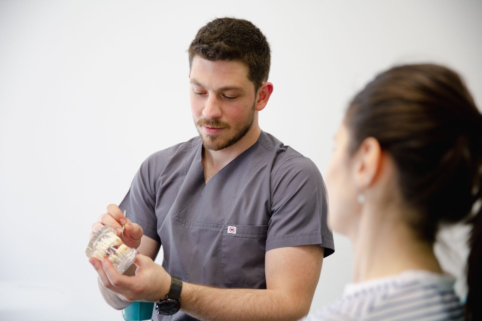 A dentist demonstrating a dental model to a patient during a consultation