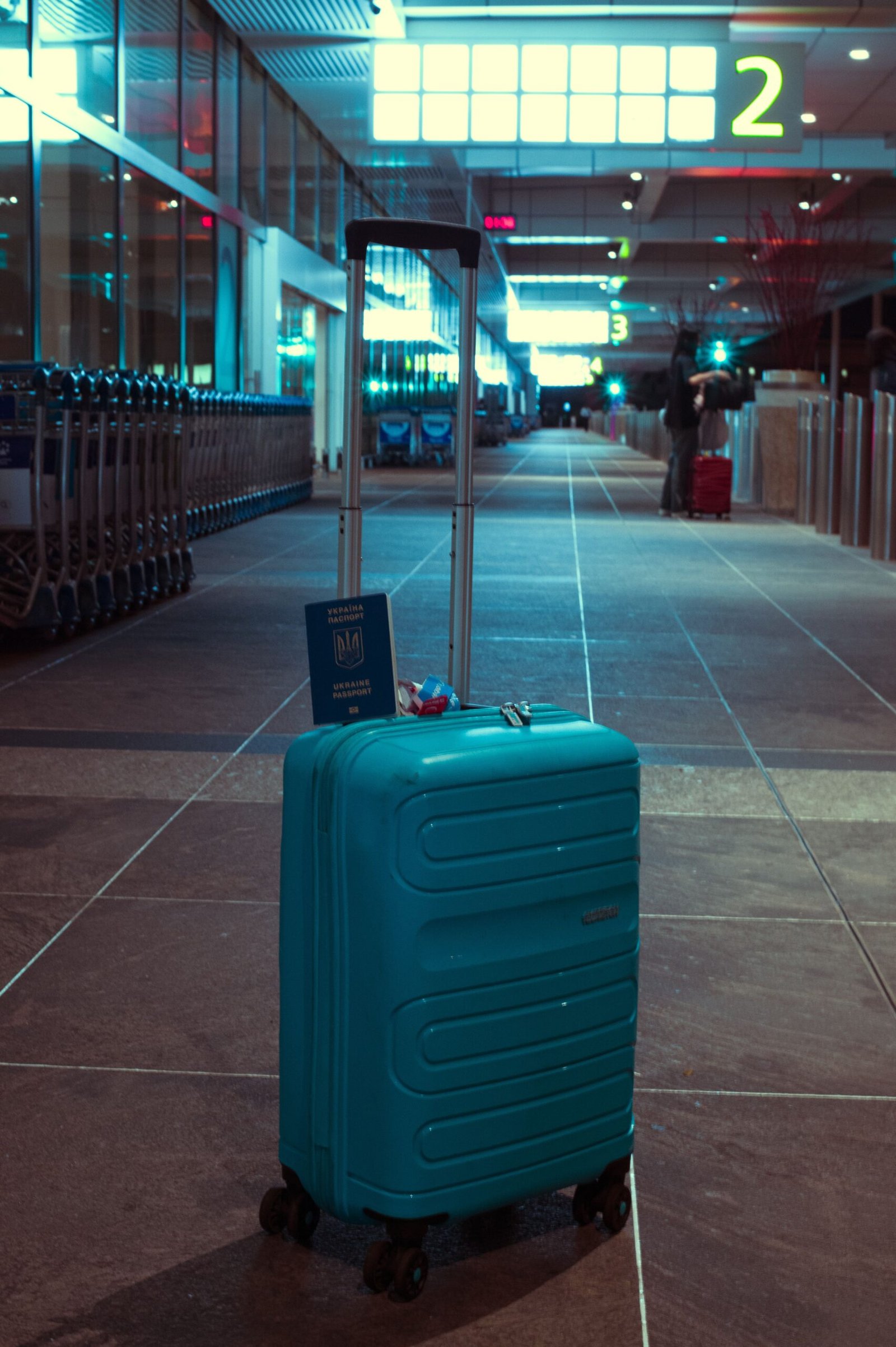 A blue suitcase displayed with a passport in an empty airport terminal