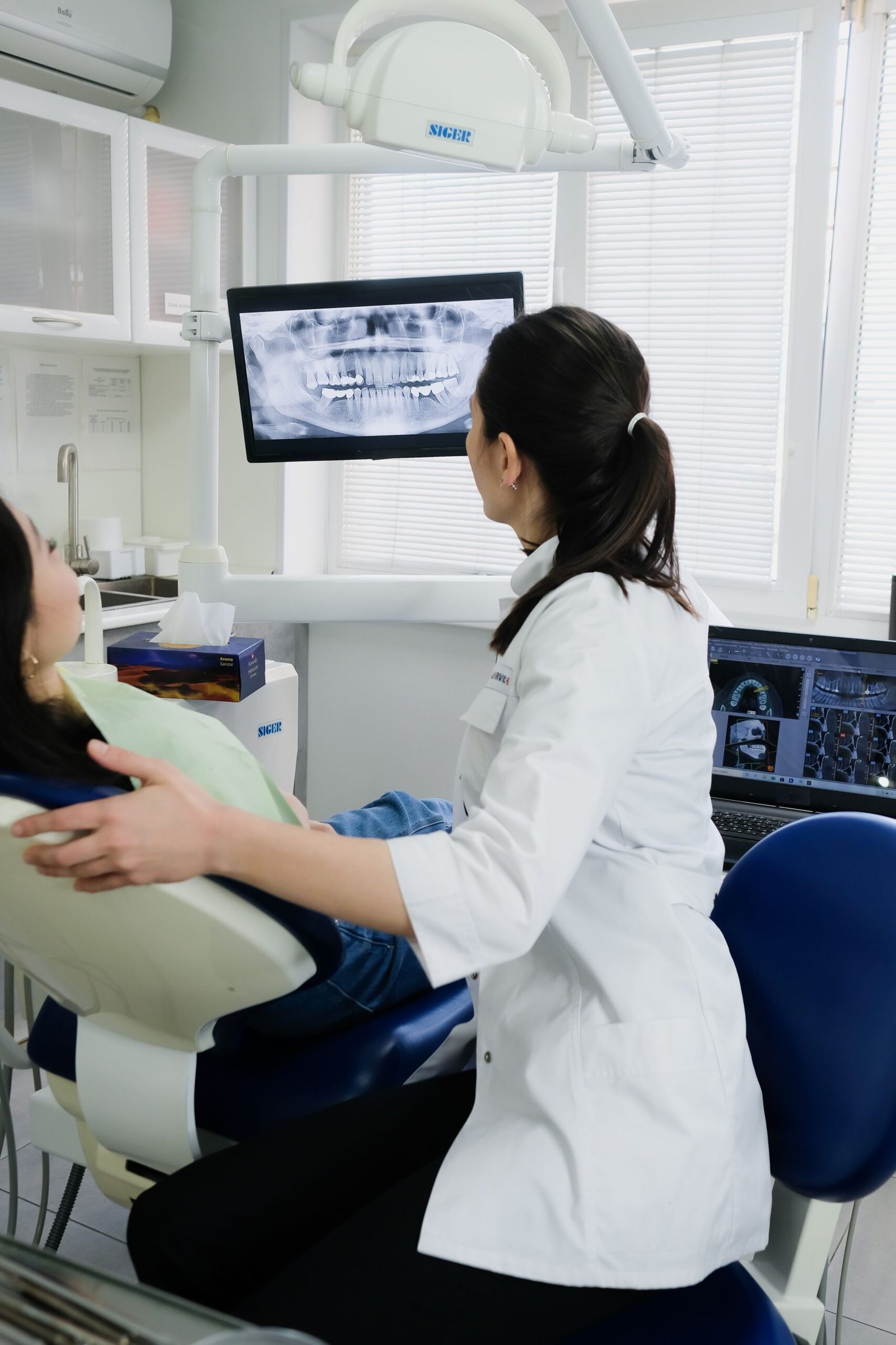 A dentist explaining X-ray results to a patient on a screen in a modern dental clinic