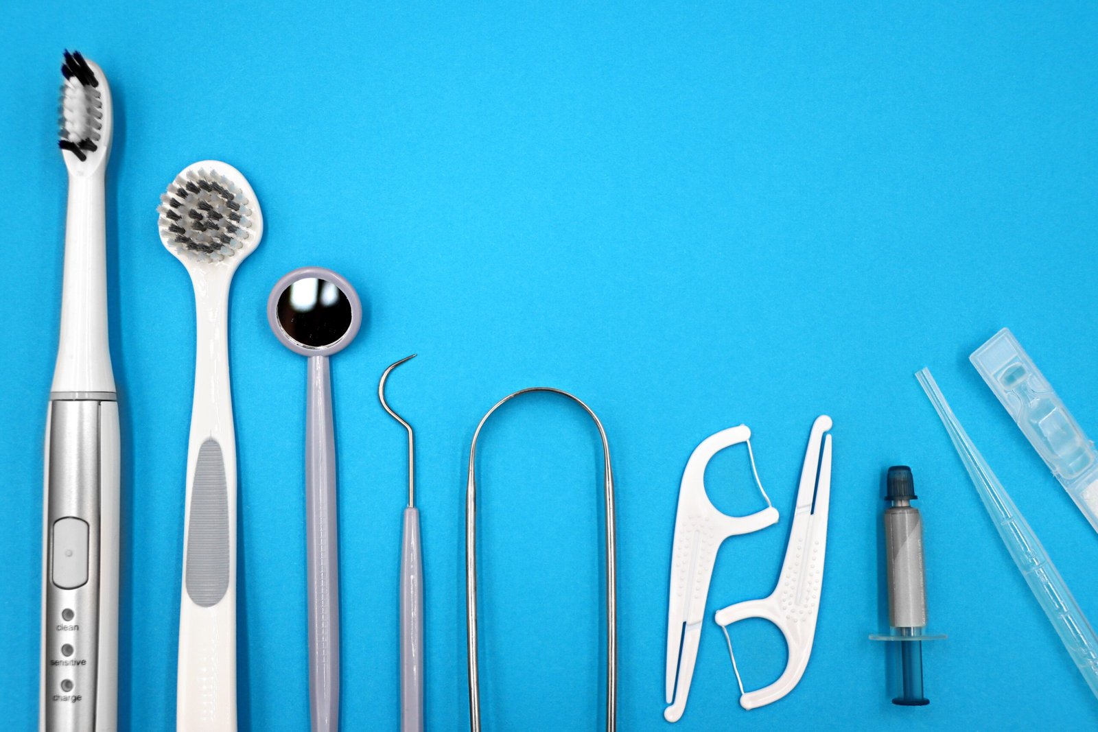 A flat lay of dental care tools on a blue background