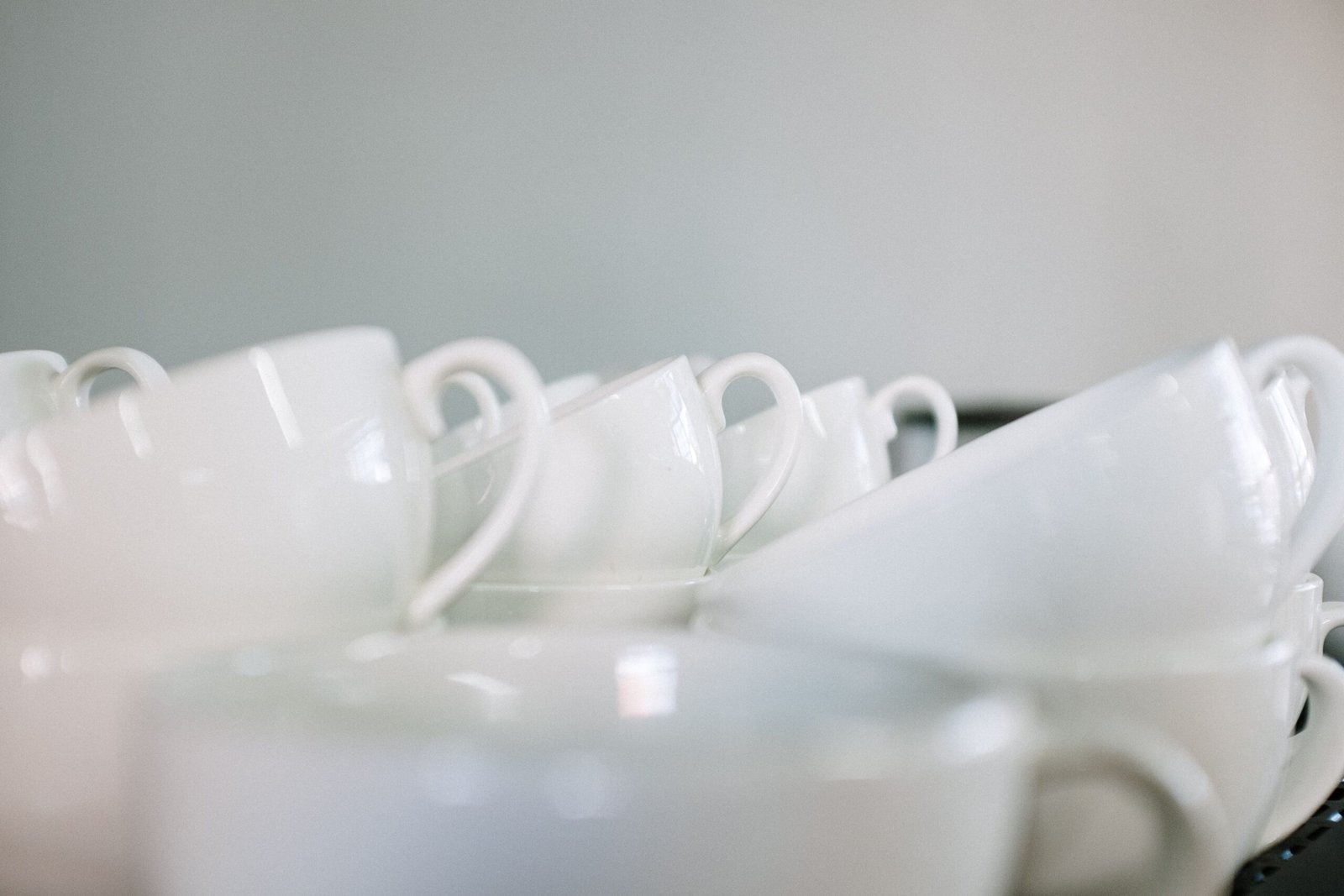 Stacked white coffee cups arranged as a minimalist still life in a café.