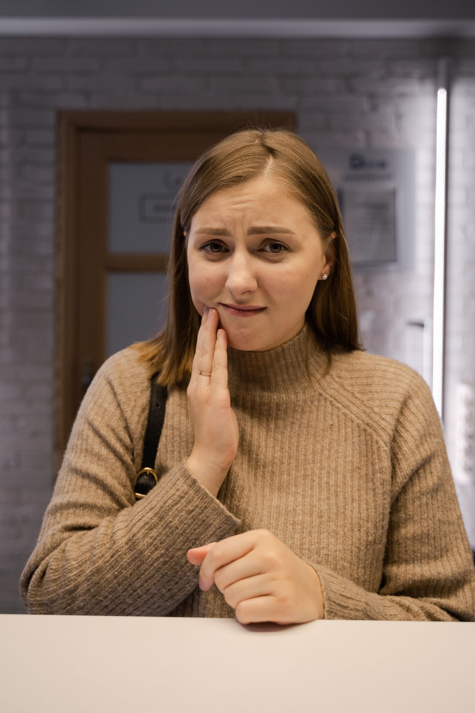 A young woman with a toothache looking uncomfortable in a dental clinic