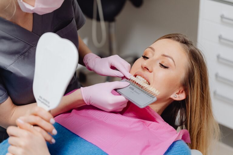 A dentist using a shade guide to match tooth color for a patient in a dental clinic.