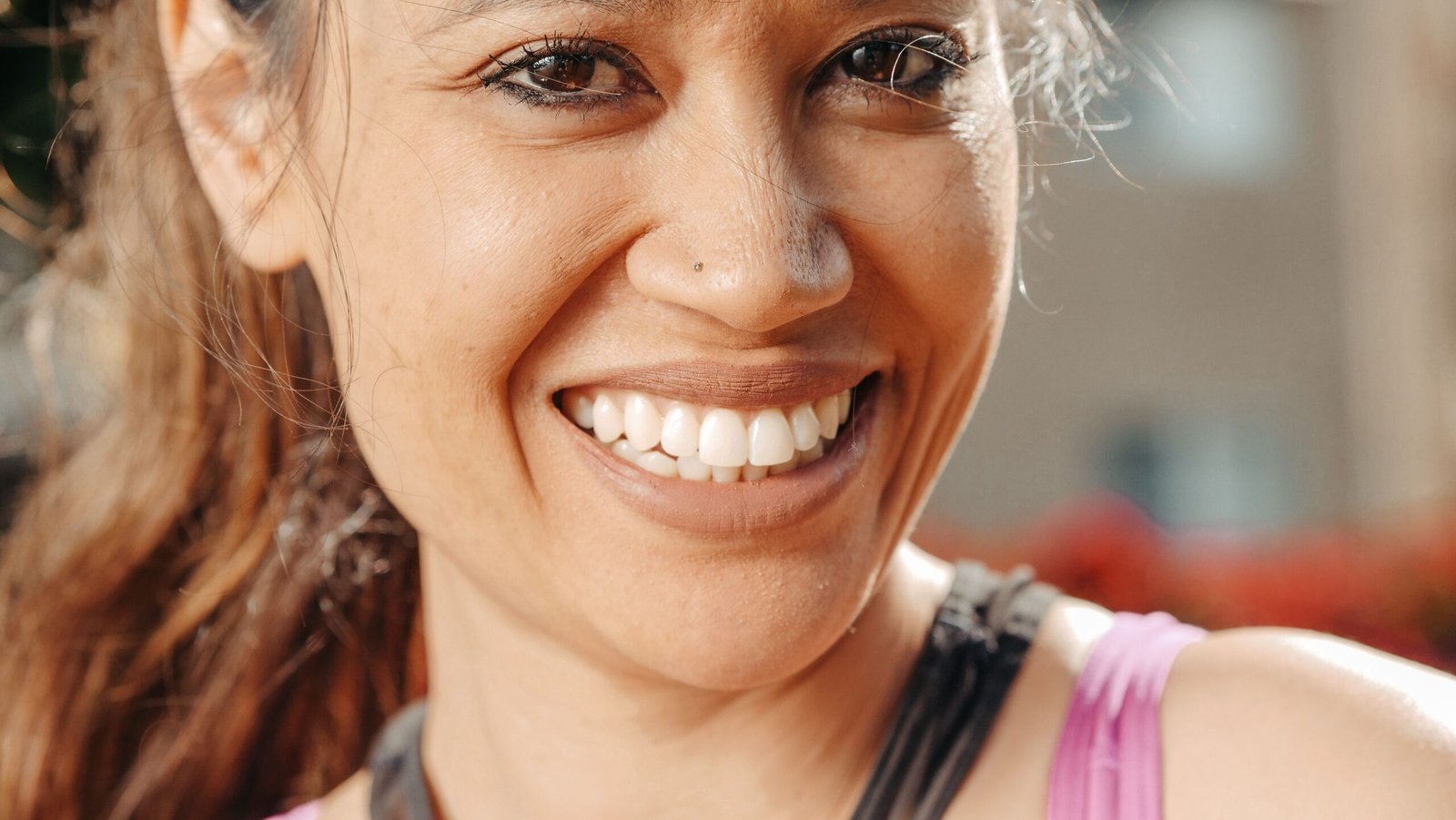 A close-up of a smiling woman outdoors on a sunny day