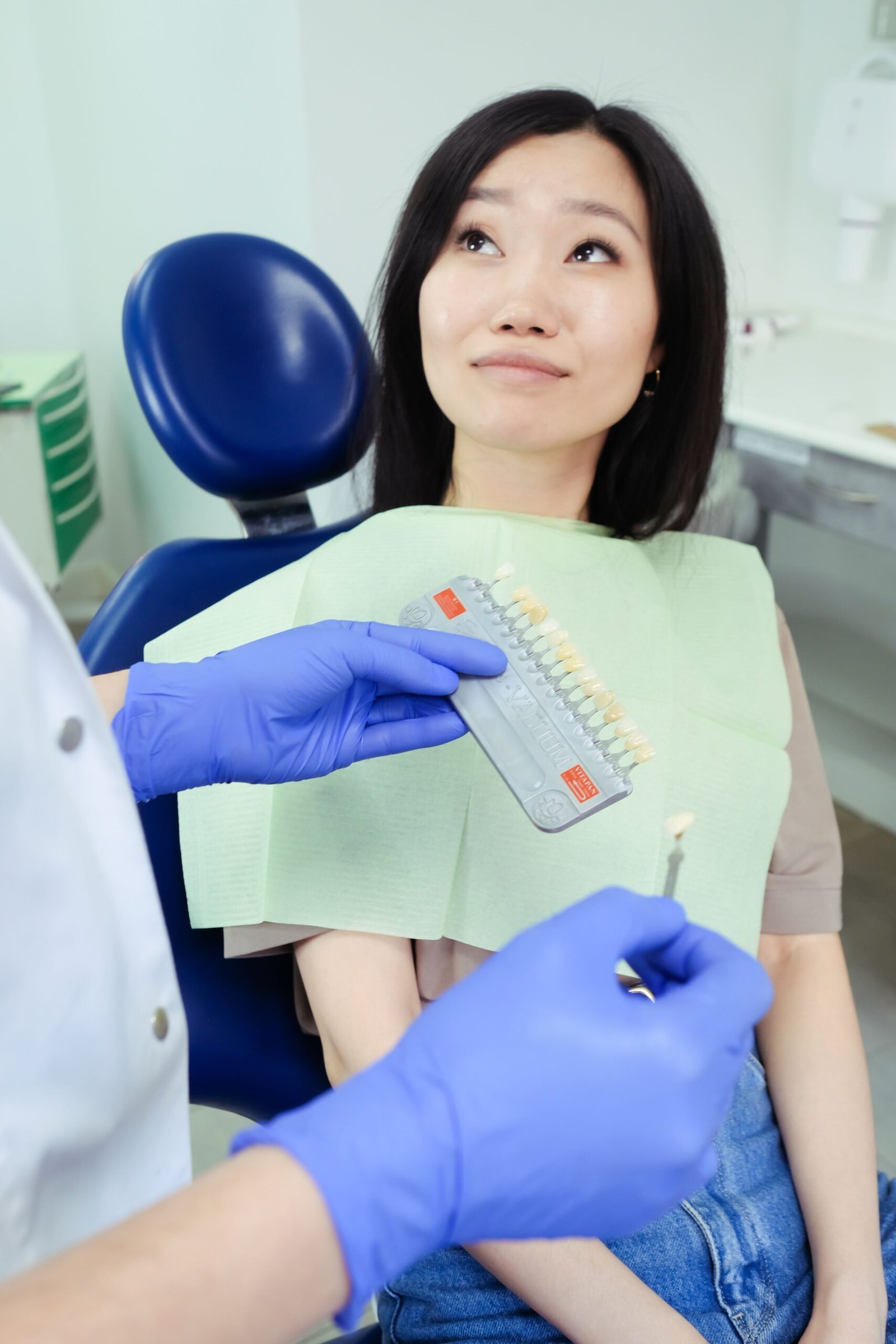 A dental professional matching a patient's teeth shade in a clinic